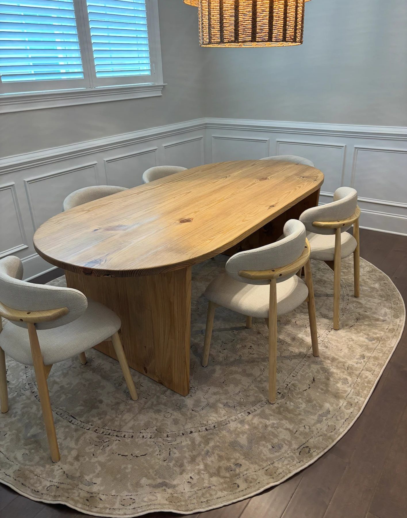 Oval farmhouse dining table on a solid panel base with upholstered chairs