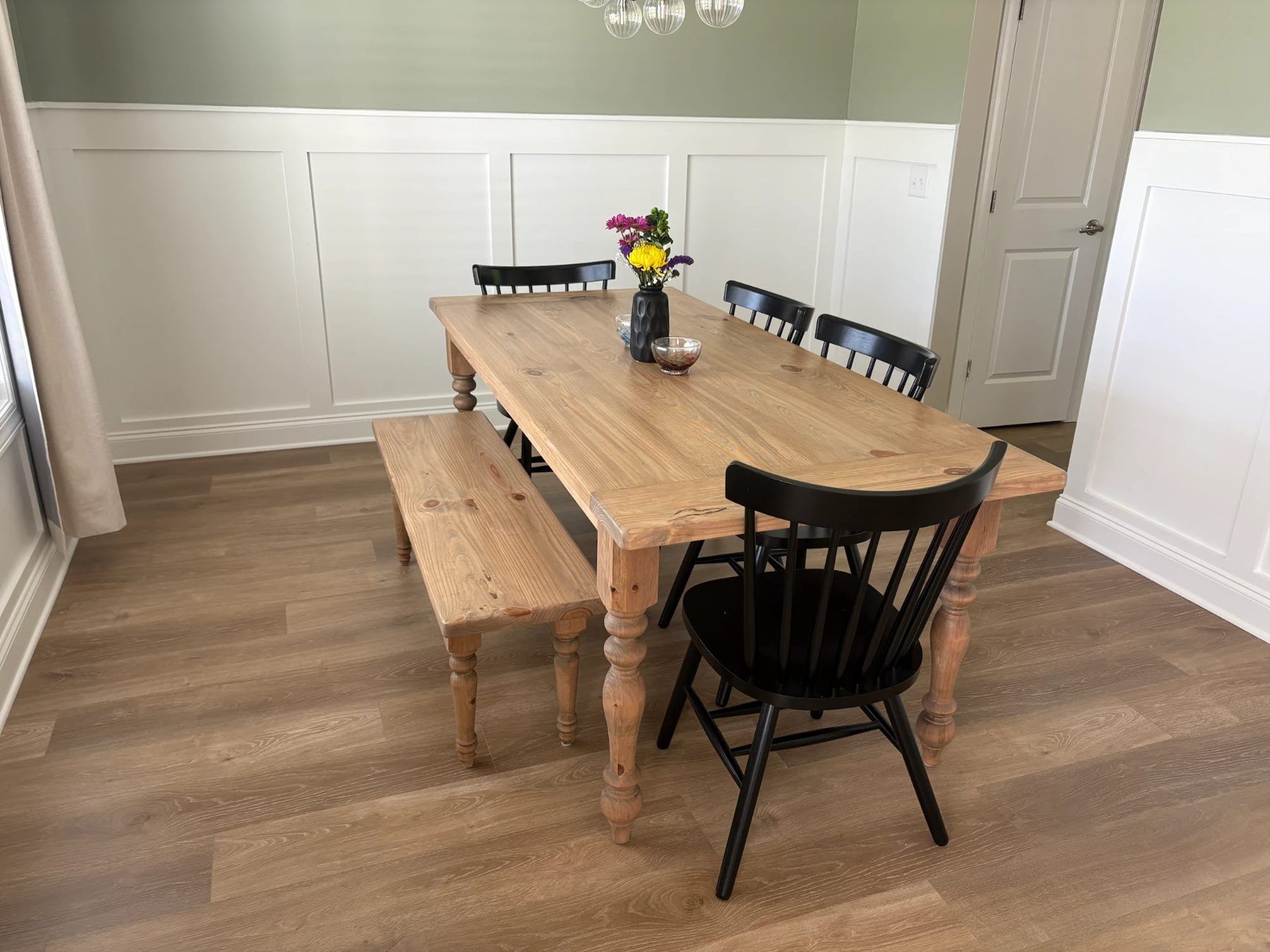 Natural pine turned leg farmhouse table with matching bench and black spindle chairs